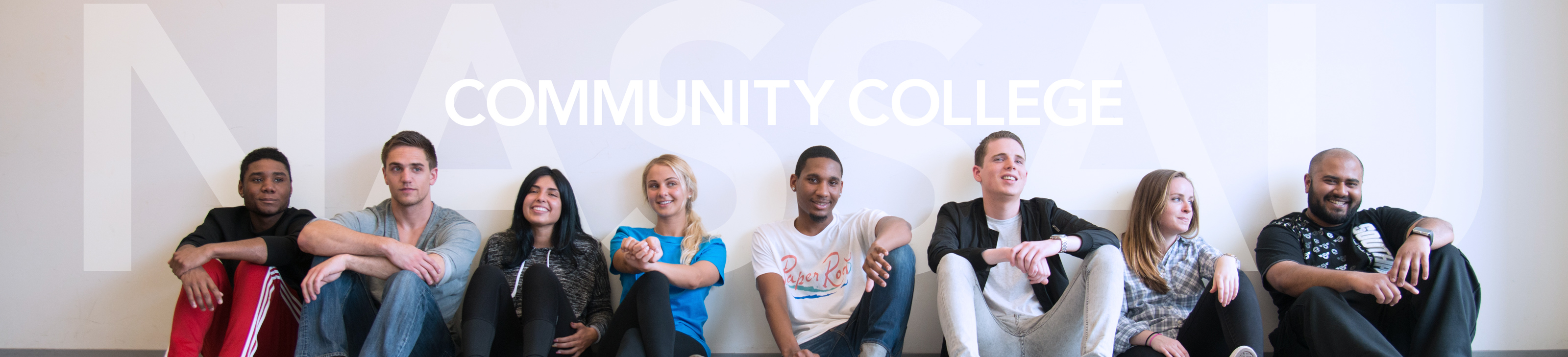 Nassau Community College. Students sitting on floor against wall. 